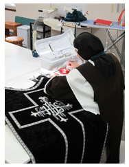 Sister sews lining to one of the Requiem vestments. sister sewing black vestment