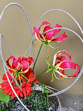 Playful arrangement of orchids and gerbera with wire accents.
