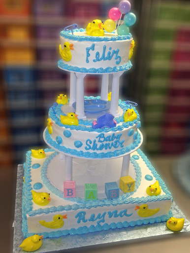 Approximate Servings 90. Sizes: 7", 10" & 1/2 Sheet. Yellow duckies accent this cake at every angle as a special addition baby blocks and baby booties are included to make this a spectacular choice for your special day.