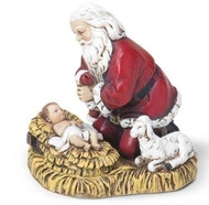 Santa holding his hat in his hands as he kneels over the manger
