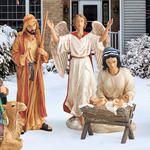 Metal Nativity set with Joseph, Mary, baby Jesus, and the angel, displayed in a yard.