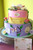 Two tiered, stacked cake. Buttercream covered. Handcrafted fondant flowers, butterflies and picture plaques.