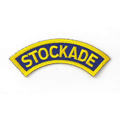 This blue curved patch with a yellow border features the word "STOCKADE" in yellow and is used on the shoulder of the Stockade uniform shirt.