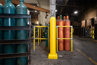 Yellow 6" x 48" Plated Bollard Cover protecting a storage area