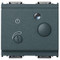 A wide dark grey switch. 2 small round knobs on the front. A small light on top center. On a white background