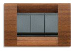 A wooden rectangle cover plate with 3 black square buttons in the center. On a white background