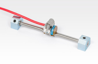 Model 4000 Vibrating Wire Strain Gauge (shown with pluck and read coil, mounting blocks and hose clamp).