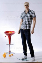 In this full body view photo, wearing a short blond wig / hairpiece, blue jeans, tennis shoes, and a plaid short-sleeved shirt, mannequin Alex stands with his left leg slighly forward along with his left arm while his right remains back - both at about hip level.  Mannequin Alex can be displayed with or without a wig / hairpiece.  Glass stand and support hardware included.