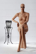In this full body view, naked mannequin Emily sits with her right leg crossed over her left and her left hand resting on her right knee. Her right hand is at her waist.   With pierced ears, mannequin Emily can display earrings and jewelry.  Pedestal included.