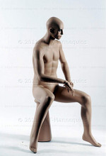 In this full body side view photo, naked mannequin Roger sits upright with his legs apart and his hands in his lap.  Mannequin Roger can be displayed with or without a wig / hairpiece.  Pedestal included.