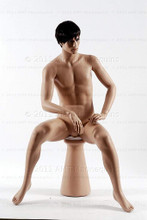 In this full body view photo, wearing a short dark brunette wig / hairpiece, naked mannequin Roger sits upright with his legs apart and his hands in his lap.  Mannequin Roger can be displayed with or without a wig / hairpiece.  Pedestal included.