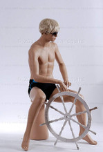 In this full body view photo, wearing a short blond wig / hairpiece and a black swim suit,  mannequin Roger sits upright with his legs apart and his hands in his lap.  Mannequin Roger can be displayed with or without a wig / hairpiece.  Pedestal included (sunglasses not).