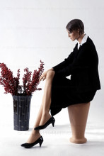 In this full body side view, wearing a black business suit with a white blouse and heels, mannequin Ruby sits with her right leg crossed over her left and her right hand resting on her right knee. Her left hand rests on her left knee.   With pierced ears, mannequin Ruby can display earrings and jewelry.  Pedestal included.