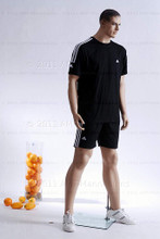 In this full body side view photo, wearing a black shorts with a short-sleeved athletic jersey, mannequin Matt stands with his legs apart in an even stance, with both hands almost straight down at hip level.  Mannequin Matt can be displayed with or without a wig / hairpiece.  Glass stand and support hardware included.