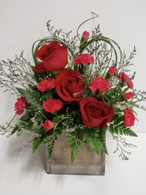 You can feel this arrangement is from the heart. Cross My Heart contains red roses, hot pink mini carnations, greens in the shape of a heart and filler flowers to fill the whitewash wooden cube container. 