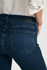 Close-up detail view of the ink brushed feather blue denim texture, back pockets, and button closure
