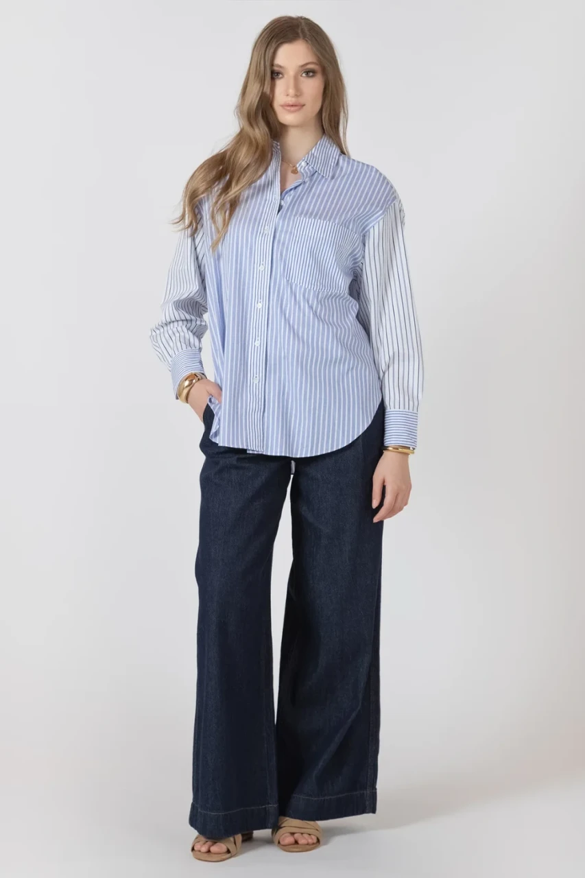 Full-length portrait of model wearing Black Tape neutral button front shirt styled with denim
