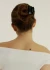 Lifestyle view of a person with a hair bun wearing the black scalloped Muse clip against a light wall