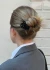 Lifestyle view of a person with a blonde hair bun wearing the black scalloped Muse clip against a light wall