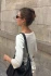 Lifestyle view of a woman standing near a stone wall with her hair half up secured in the small honey demi clip