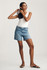 Full-length portrait of model wearing light brushed classic blue Mavi Heidi long denim shorts styled casually