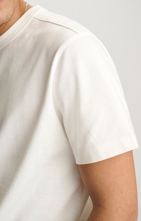 Close-up detail view of the soft antique white cotton knit texture and collar ribbing