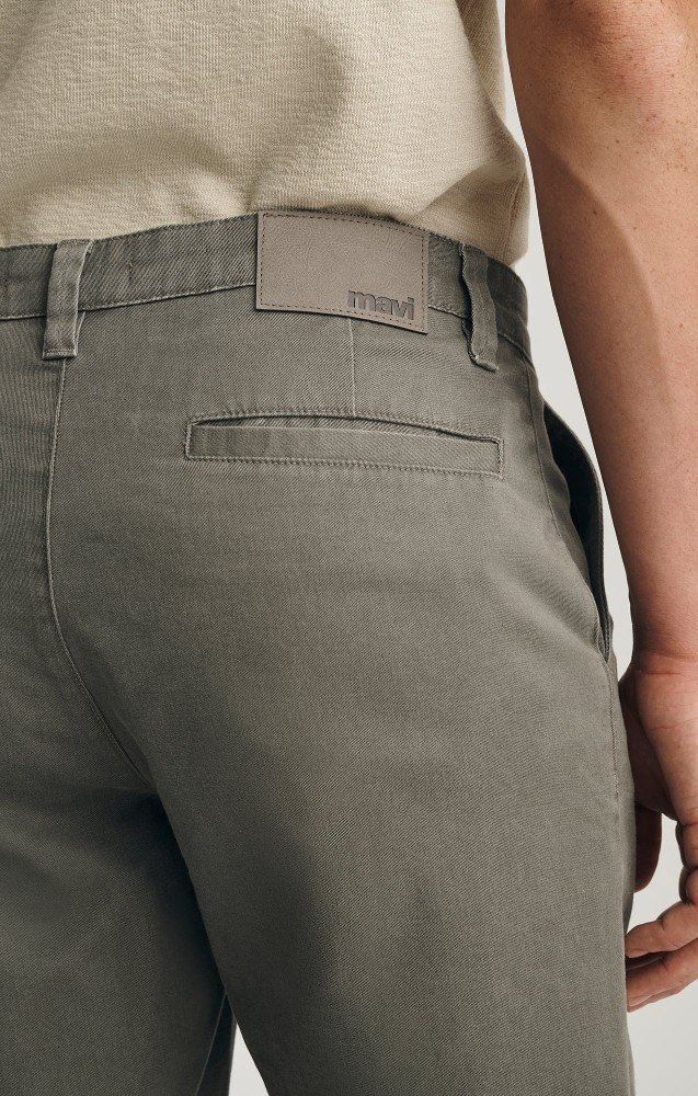 Close-up detail view of the olive vintage colored stretch denim texture and back pocket