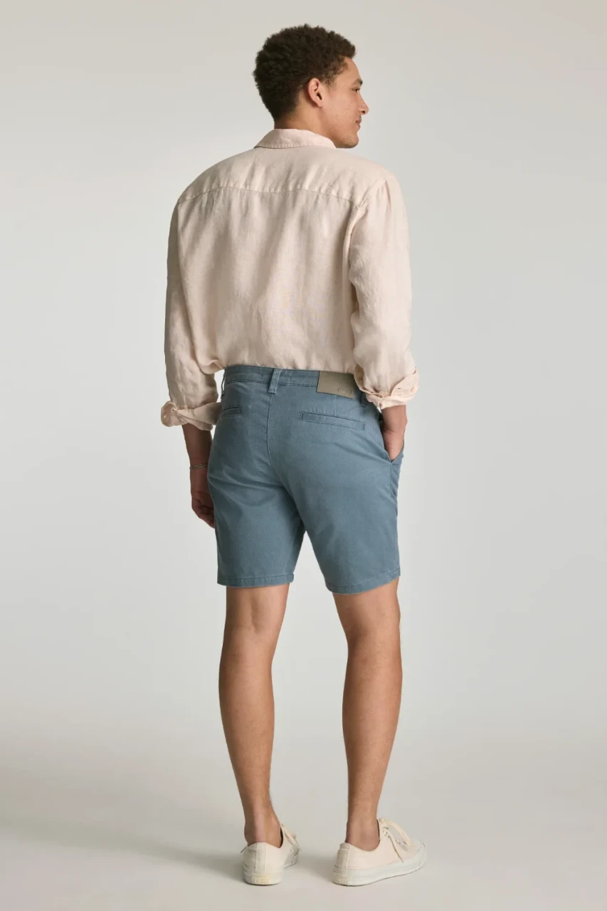 Back view portrait of model wearing faded blue vintage colored Mavi Noah slim shorts styled casually