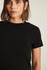 Close-up detail view of the soft black cotton-elastane ribbed knit texture and crew neckline