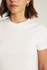 Close-up detail view of the soft white cotton-elastane ribbed knit texture and crew neckline