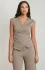 Front view of a woman wearing a fitted sleeveless cross-wrap V-neck top and matching neutral wide-leg pants set.