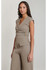 Three-quarter side angle of a woman in a neutral stretch-knit sleeveless wrap top and high-waisted trousers.