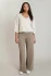 Full-length portrait of model wearing Dex V-neck sweater top in soft oatmeal mix styled with dark trousers