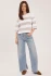 Full-length portrait of model wearing heather cream stripe Gentle Fawn Amina top styled with denim