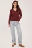 Full-length portrait of model wearing bordeaux Gentle Fawn Carina pullover styled with denim