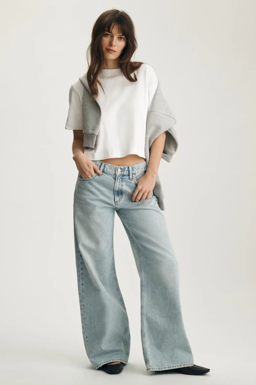 Full-length portrait of model wearing white Mavi Riley crew neck t-shirt styled with wide-leg jeans