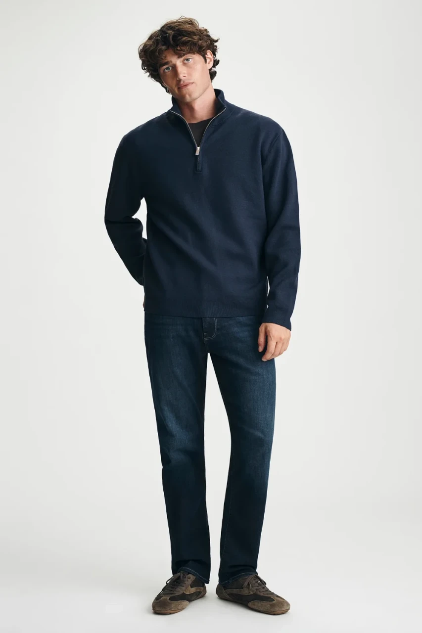 Full-length portrait of model wearing navy Mavi quarter-fit zip sweater styled casually with denim