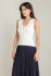 3/4 portrait of model wearing Black Tape cream scalloped knit top styled with denim