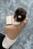 Lifestyle view of a person seated from behind on a textured blue-gray carpet reading with a pearl hair clip in her hair