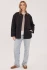 Full-length portrait of model wearing black Gentle Fawn Felix quilted jacket styled with denim