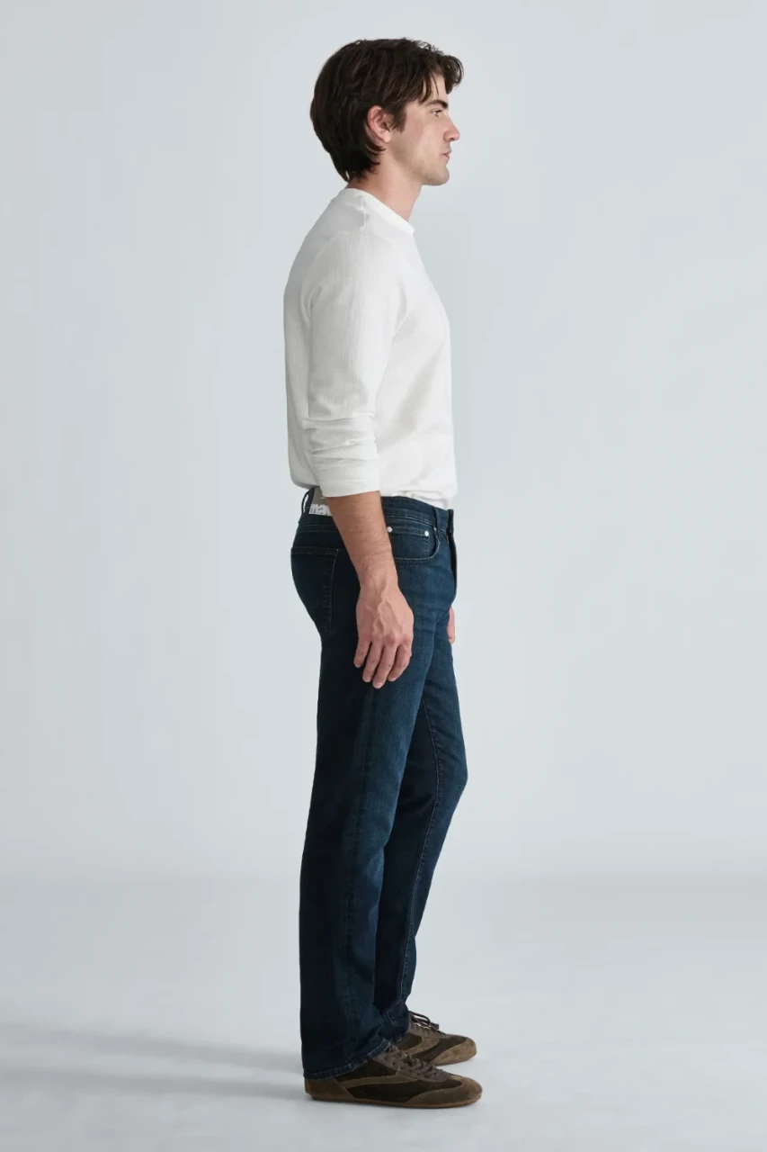 Side view of model wearing Mavi Marcus deep indigo jeans highlighting the slim straight leg fit and clean hem