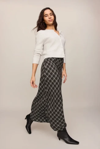 Full-length portrait of model wearing ash black plaid Z Supply Europa maxi skirt styled with a cozy knit top