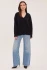 Full-length portrait of model wearing black Gentle Fawn Tilda bouclé sweater styled with denim