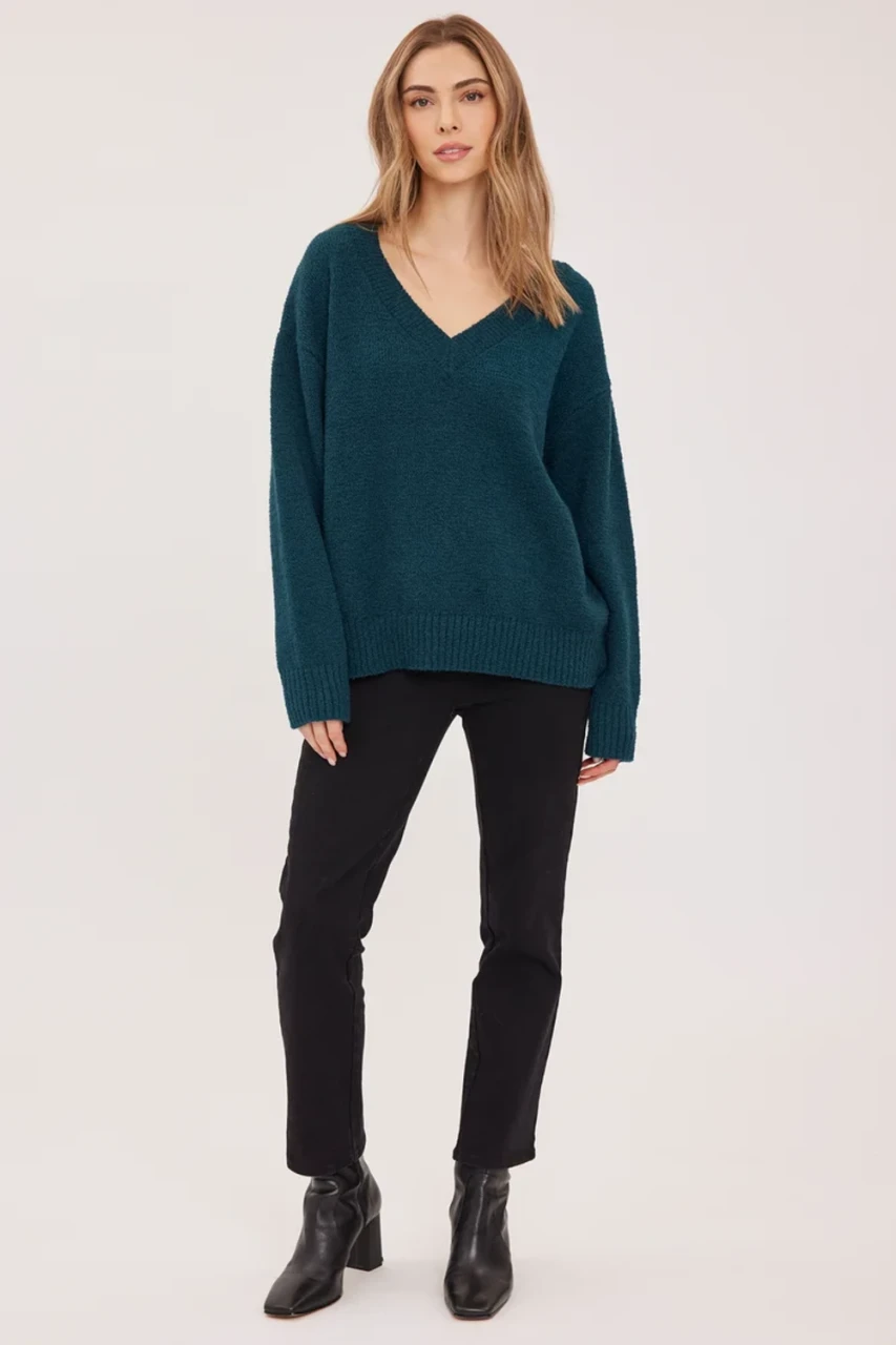 Full-length portrait of model wearing spruce green Gentle Fawn Tilda bouclé sweater styled with denim