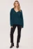 Full-length portrait of model wearing spruce green Gentle Fawn Tilda bouclé sweater styled with denim
