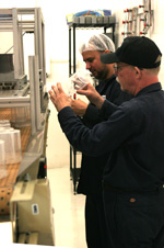 Two employees in uniforms and caps, working