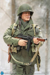 A close up showing the highly detailed and lifelike face sculpt of the DID Lieutenant Buck figure wearing a netted M1C helmet.