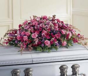 An abundance of purple flowers are lavished upon this casket spray to convey your affection.