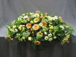 A full casket spray of peach Gerbera, yellow, white, and peach Alstroemeria, Versillia Roses, white and yellow Daisies, Queen Anne's Lace, and mixed foliage. This is for a closed casket.