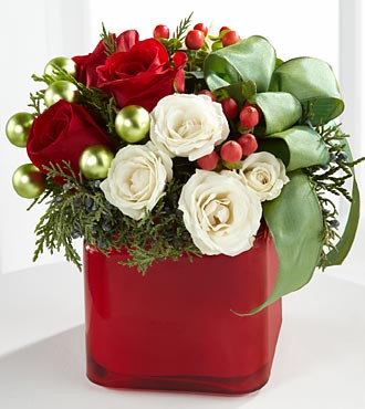 The  Merry & Bright™ Bouquet we make this using vibrant red roses, white spray roses, red hypericum berries and assorted holiday greens create a stunning look with green glass balls and green taffeta ribbon nestled within the arrangement. Arranged in a red glass cube vase, this bouquet is guaranteed to make their holiday both merry and bright.